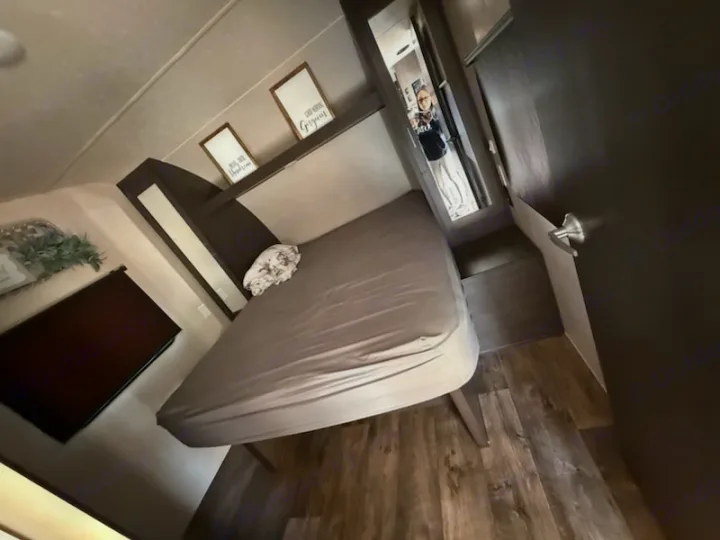Compact RV rental bedroom featuring a comfortable bed, wood-look floor, and charming wall decor for your travels.. Forest River Salem 2019