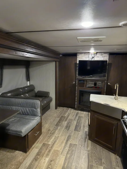 Cozy RV rental interior. Features a living area, dinette, kitchen, fireplace, and TV. Ideal for comfortable travel.. Forest River Cherokee Alpha Wolf 2018