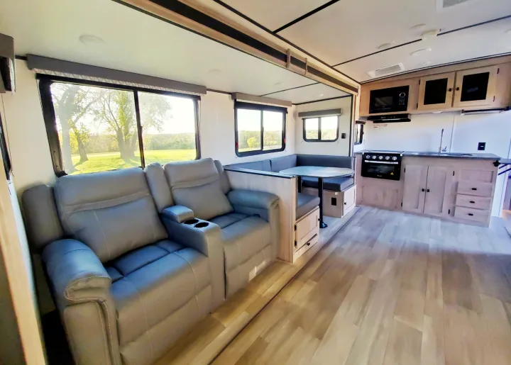 Inside a modern RV rental: comfortable recliners, a dining booth, and a fully equipped kitchen.. Coachmen Northern Spirit 2024