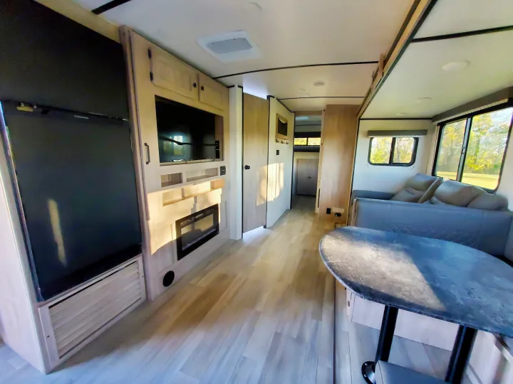 Modern RV rental interior featuring a Furrion TV, electric fireplace, large fridge, dinette, and bright windows.. Coachmen Northern Spirit 2024