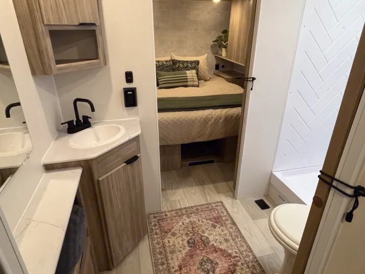 RV rental interior: modern bathroom with sink & shower, plus a cozy bedroom area. Perfect for a comfortable road trip.. Winnebago Access 26 RL 2024