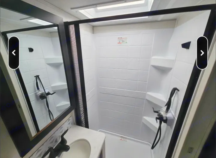 Spacious RV rental bathroom featuring a modern white shower, built-in shelves, and a vanity area with a sink.. Forest River Surveyor Legend 19SSLE 2024