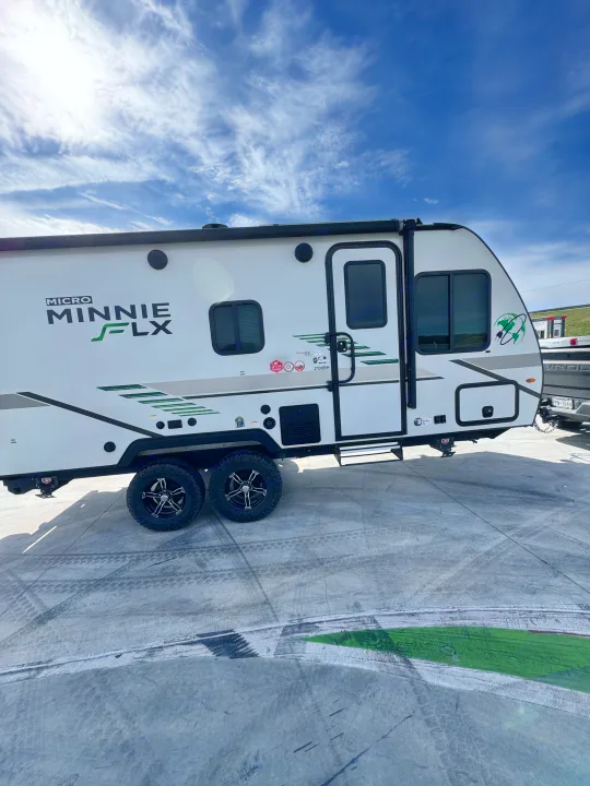 White Micro Minnie FLX travel trailer on concrete, under a blue sky with wispy clouds. Great for your next RV rental.. Winnebago Micro Minnie FLX 2100BH 2022