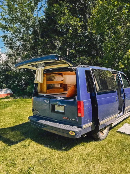 Blue GMC Safari van converted for camping, showcasing its interior setup. A great RV rental option for nature lovers.. Gmc Safari 1996