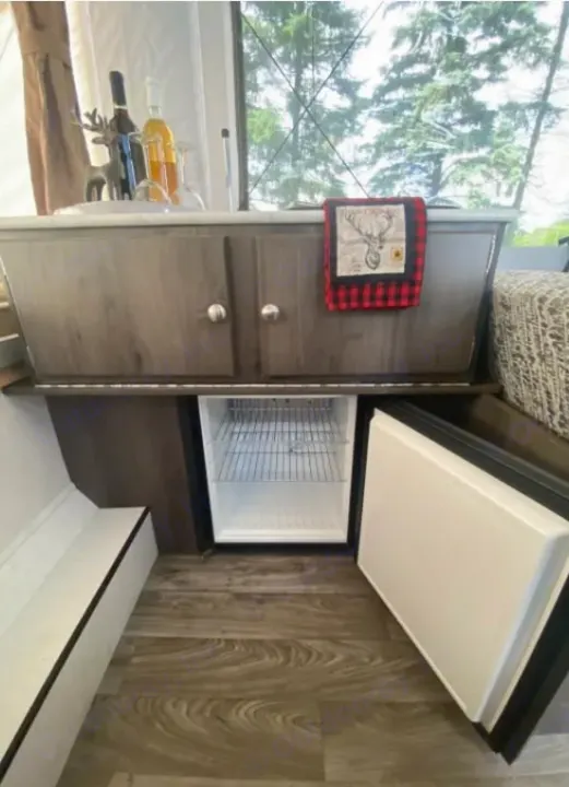 RV rental: Cozy interior with wood-look cabinets, open mini-fridge, and rustic decor like a deer towel and statue.. Coachmen epic 1906 2019