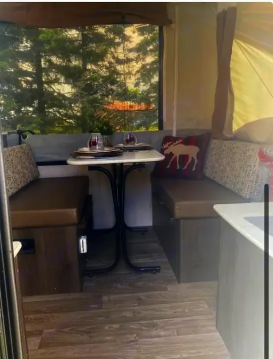 Inside your next RV rental: a bright camper dining area with a table, cozy bench seating, and a scenic forest view, perfect for travel.. Coachmen epic 1906 2019