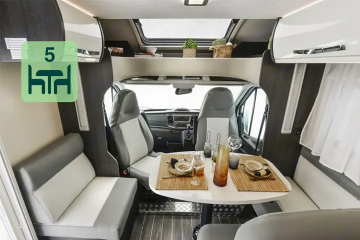 This RV rental interior offers a comfortable dining area designed for 5 people, converting driver seats to dinette.. Roller Team 696 2024
