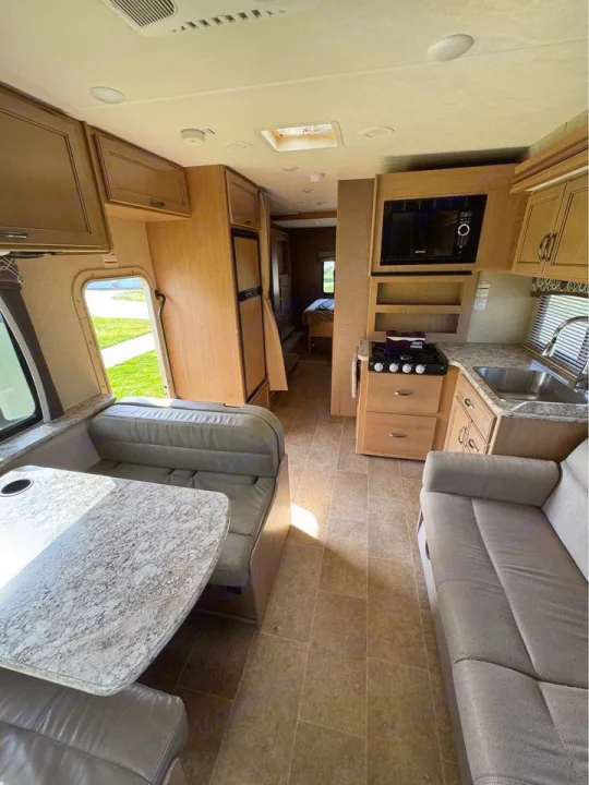 Spacious RV rental interior featuring a full kitchen, dinette, and living area with a sofa. Bedroom in back.. Thor Motor Coach Chateau 2019