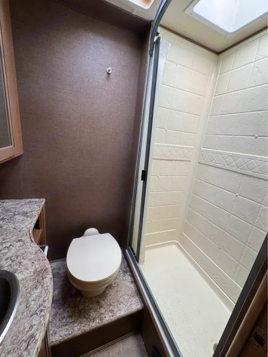 Compact RV rental bathroom featuring a shower stall, toilet, and small vanity with a sink.. Thor Motor Coach Chateau 2019