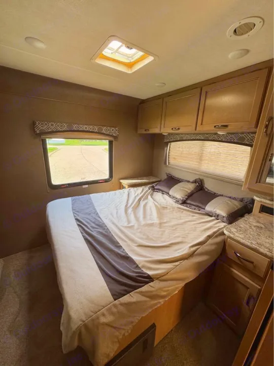 Cozy RV rental bedroom featuring a bed, window with outdoor view, overhead cabinets, and ceiling skylight.. Thor Motor Coach Chateau 2019