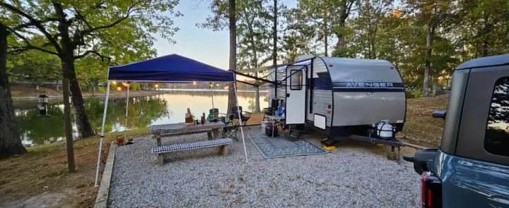 Lakeside RV rental camping setup, showing a travel trailer, picnic table, and canopy. Perfect for outdoor adventures.. Avenger LT 2022