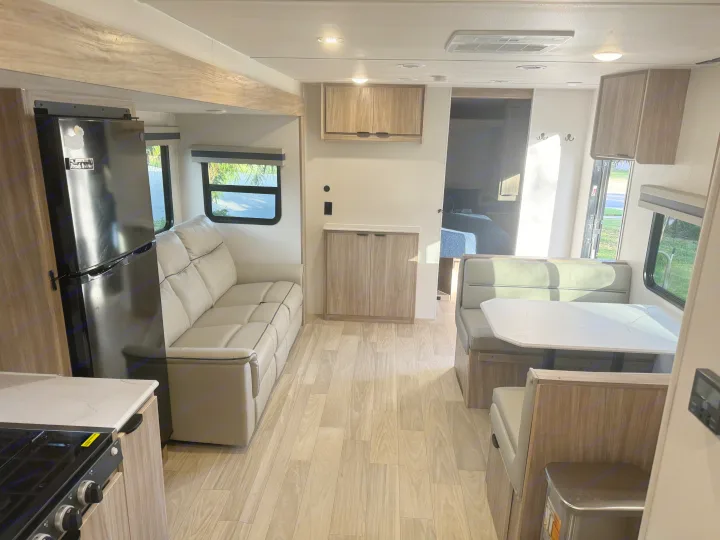 Spacious RV rental interior featuring a living area with a sofa, kitchen appliances, and a dining booth.. Winnebago Access 2024