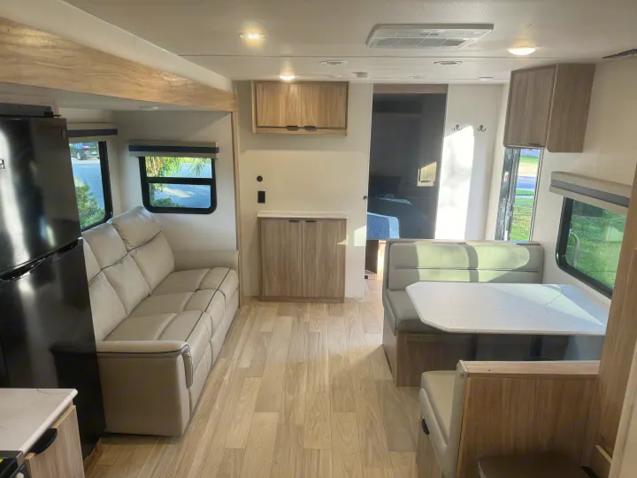 Bright, modern RV rental interior with a comfy sofa, dinette, and light wood-look flooring. Ready for adventure.. Winnebago Access 2024