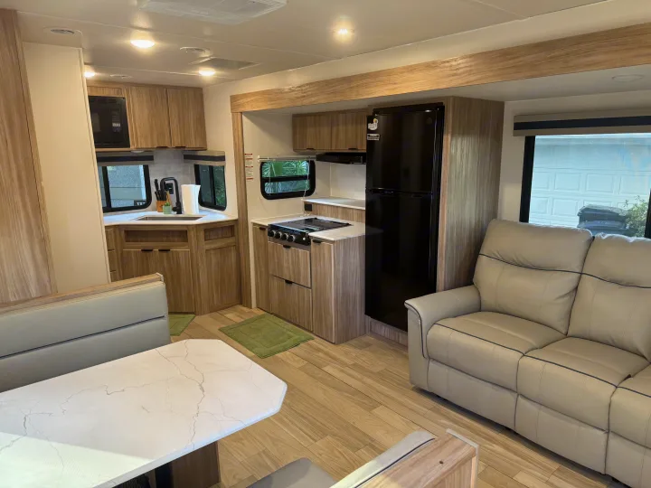 Spacious RV rental interior featuring a modern kitchen, dining booth, and recliner sofa for comfortable travel.. Winnebago Access 2024