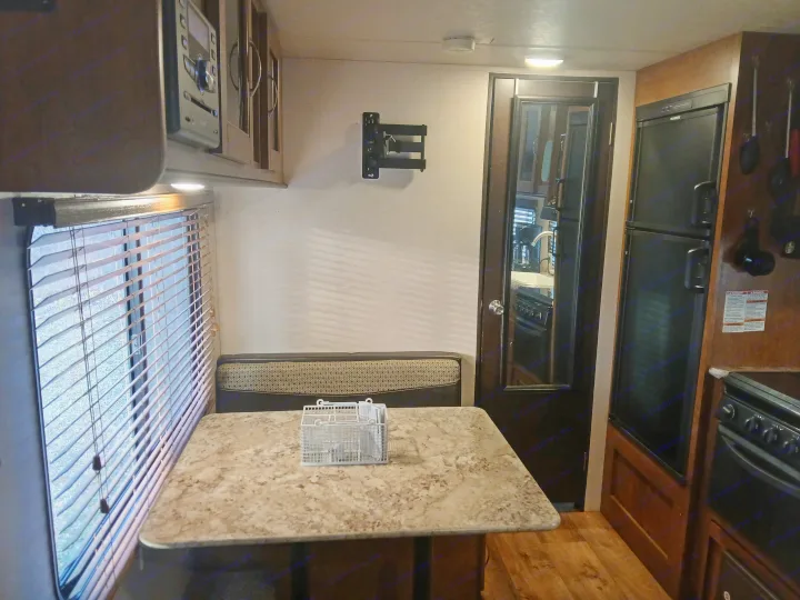 Inside an RV rental: a compact living area with a dinette, kitchen appliances (fridge, stove), and window blinds.. Forest River Salem Cruise Lite 2018