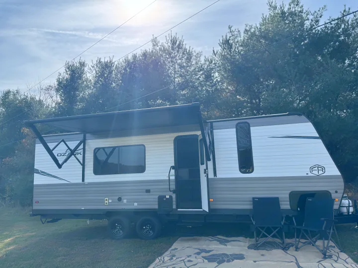 Ozark travel trailer RV rental, with an extended awning and outdoor chairs, ready for a relaxing getaway.. Forest River Ozark 2025
