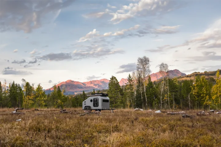 Compact RV rental camper in a scenic mountain landscape with autumn trees, bathed in golden hour light, perfect for outdoor trips.. Campworks NS-1 Electrified 2024