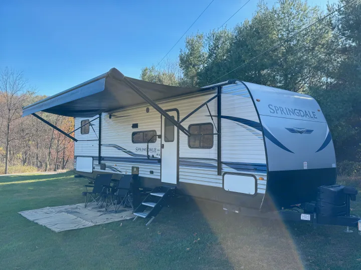 Enjoy this bright Springdale RV rental, a cozy travel trailer with awning and outdoor seating on a sunny day.. Keystone RV Springdale 2021
