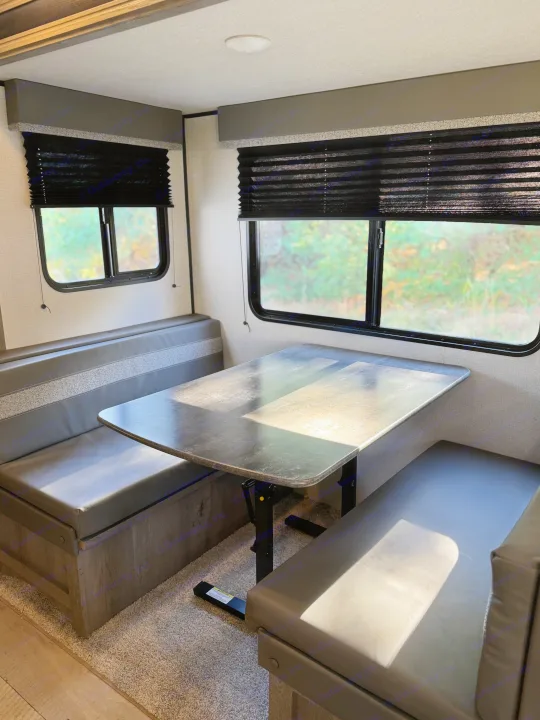 RV rental dinette: a modern space with comfortable U-shaped seating, an adjustable table, and window blinds.. Keystone RV Springdale 2021