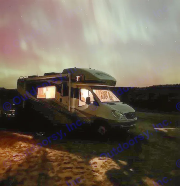 A cozy RV rental illuminated under the vibrant green and pink aurora borealis in a dark night sky.. Winnebago View 2011