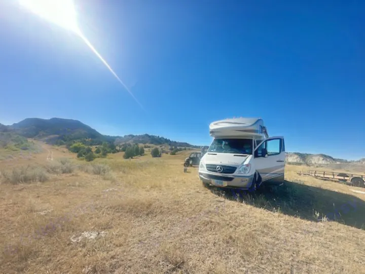 RV rental adventure: a white camper van in a sunny, dry landscape with mountains and clear blue sky.. Winnebago View 2011