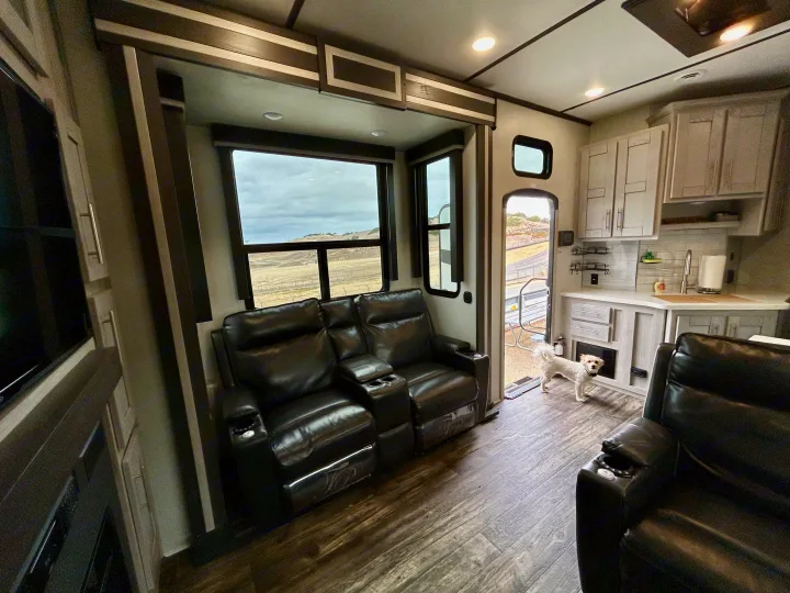 RV rental interior: comfy recliners, kitchen, and a dog, with scenic views outside. Ideal for road trips!. Keystone Fuzion 2022