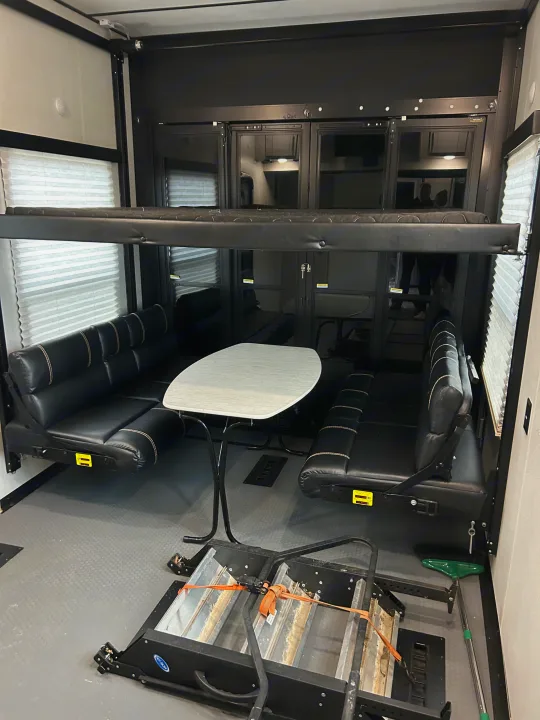 RV rental: Toy hauler interior with black dinette, fold-down bunk, and a folded cargo ramp.. Keystone Fuzion 2022