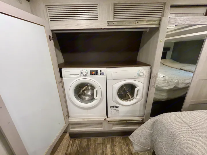 Side-by-side compact washer and dryer by Splendide in an RV rental. Efficient laundry solution next to bunk beds.. Keystone Fuzion 2022
