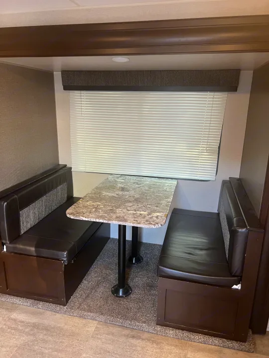 RV rental dinette: view of the booth seating, patterned table, and white window blinds in the interior.. K-Z Manufacturing Sportsmen 2019
