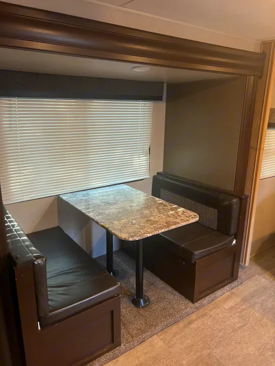 RV rental: Interior shot of a compact dinette featuring dark bench seats, a gray speckled table, and window blinds.. K-Z Manufacturing Sportsmen 2019