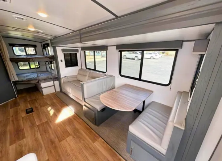 Explore this spacious RV rental interior: cozy bunk beds, a comfy sofa, and a versatile dinette area.. Keystone RV Bullet Ultra Lite 2023