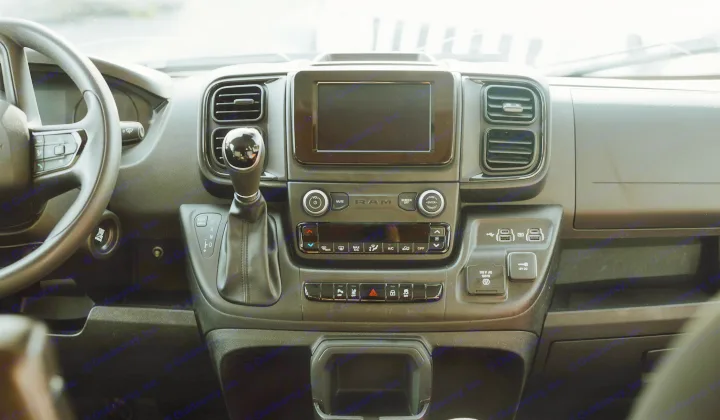 Interior view of a modern RV rental dashboard, featuring the steering wheel, shifter, infotainment screen, and power outlets.. Dodge Van 2024