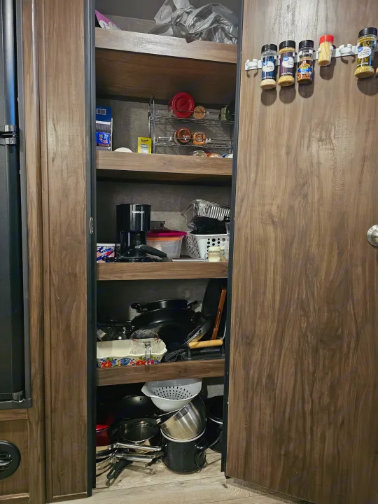 An RV rental kitchen pantry with shelves full of organized cooking essentials, spices, and a coffee maker.. Forest River Cherokee Grey Wolf 2019