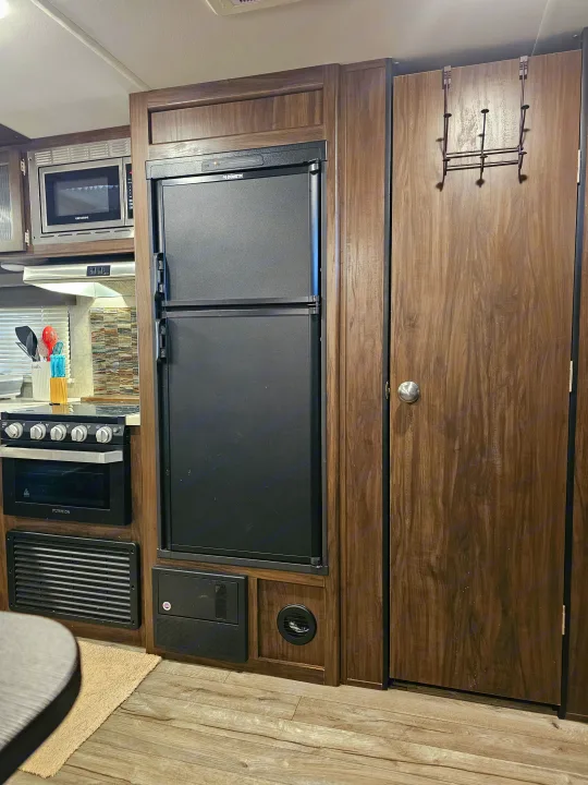 Compact RV rental kitchen with Dometic fridge, Greystone microwave, and Furrion oven, plus wood cabinetry. Ideal for travel.. Forest River Cherokee Grey Wolf 2019