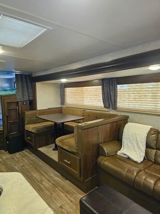Cozy RV rental interior featuring a U-shaped dinette, comfortable sofa, and bunk beds, ideal for family travel.. Forest River Cherokee Grey Wolf 2019