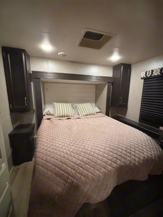 Cozy RV rental bedroom with a comfortable bed, convenient overhead storage cabinets, and soft lighting.. Entegra Coach Odyssey 2021