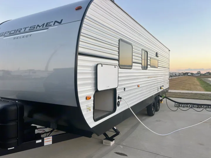 Grey Sportsmen Select RV rental, fully set up at an RV park with water and sewer hookups visible.. Other Other 2024