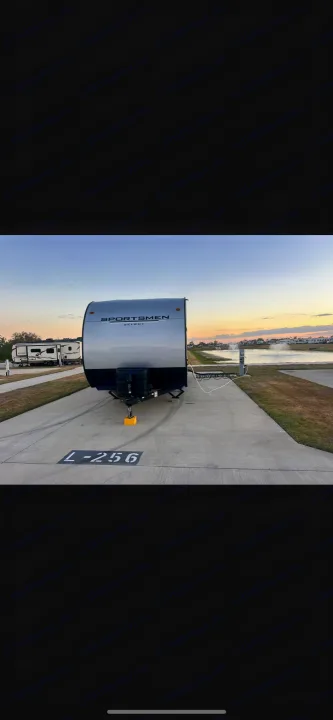 RV rental ready: a Sportsmen Select travel trailer at campsite L-256 by a scenic lake at dusk.. Other Other 2024