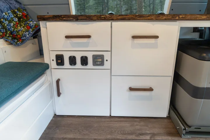 Inside this RV rental, find efficient white cabinetry, power controls, and a pull-out fridge in a compact campervan setup.. Ford Econoline 150 2009