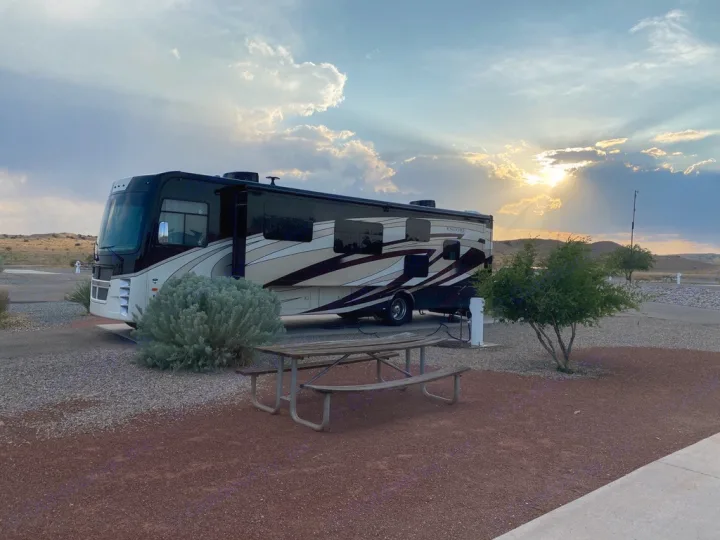 A spacious RV rental motorhome parked at a scenic campground during a beautiful sunset. Ideal for road trips.. Coachmen Encore 2022