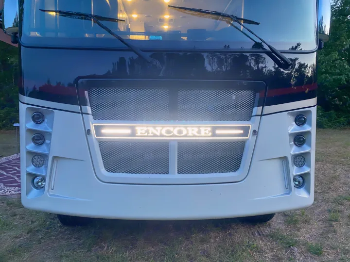 Bright front of a modern RV rental, featuring its illuminated "ENCORE" grille and multi-light design.. Coachmen Encore 2022