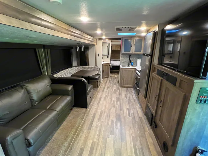 Step inside this modern rv rental. View of living area with couch, dining booth, and full kitchen. Ready for adventure!. Forest River Vibe 2020