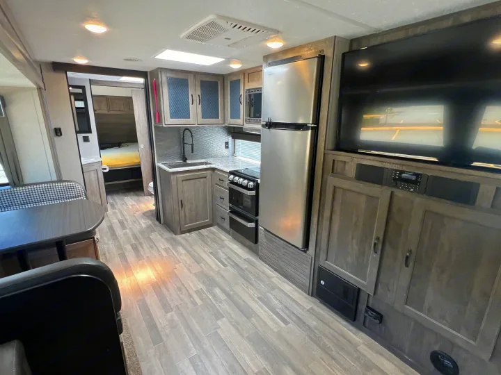 Spacious rv rental interior features a modern kitchen, dining area, and visible bedroom, perfect for travel.. Forest River Vibe 2020