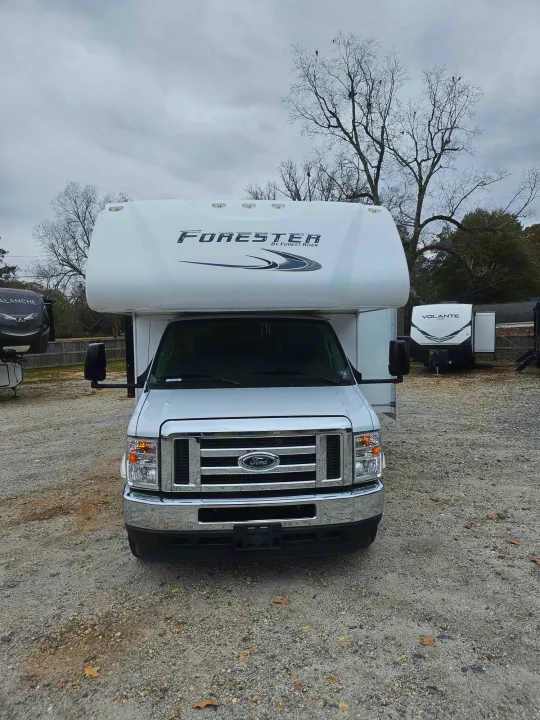 Front view of a white Ford Forester Class C RV parked on a gravel lot under an overcast sky. Inquire about rv rental!. Forest River Forester 2021