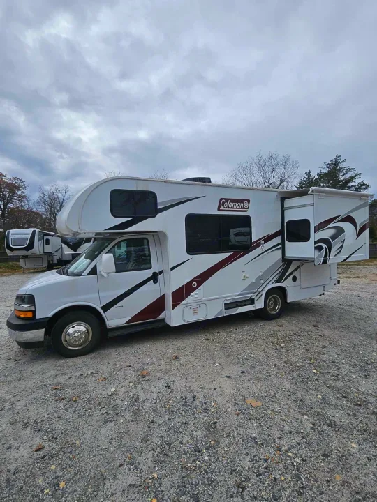 This white Coleman motorhome, with its slide-out extended, is ready for your RV rental adventure on a gravel lot.. Thor Motor Coach Other 2024