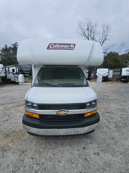 Head-on view of a white Coleman RV rental, a recreational vehicle parked on a gravel lot, ready for travel.. Thor Motor Coach Other 2024