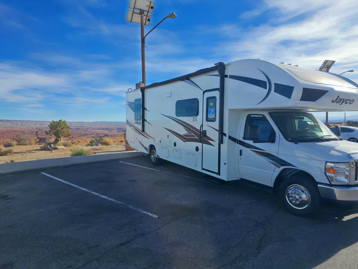 White Jayco rv rental parked at a scenic desert overlook, with a solar light. Blue sky, distant mesas. Ready for adventure!. Jayco Redhawk 2024