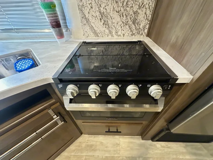 Compact RV rental kitchen featuring a Furrion stove, oven, and sink area. Ideal for road trip cooking and living.. Avenger Avenger Trailer 2022