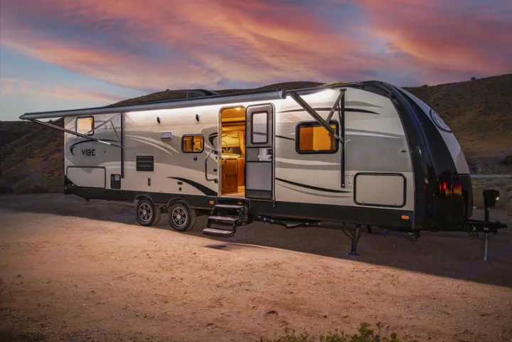 Experience adventure with this Vibe travel trailer RV rental, glowing warmly against a stunning sunset backdrop.. Forest River Vibe 2018