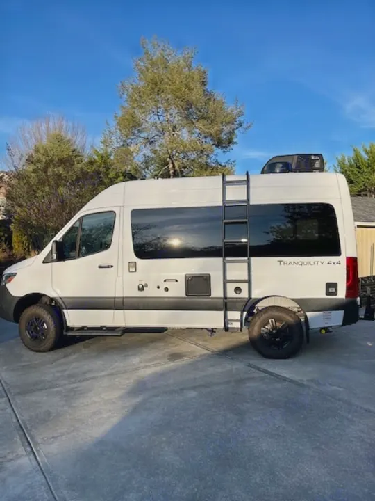 This white Tranquility 4x4 camper van is a rugged rv rental option, featuring a side ladder and ready for adventure.. Thor Tranquility 2023